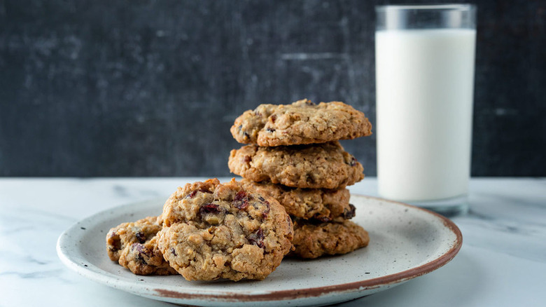 Stack of oatmeal fruit cookies on plate with milk.