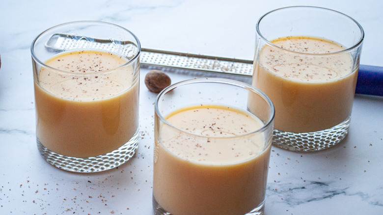 Three small glasses of eggnog with grated nutmeg