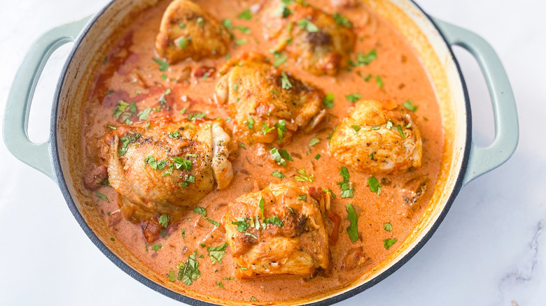 White pot with chicken thighs in sauce