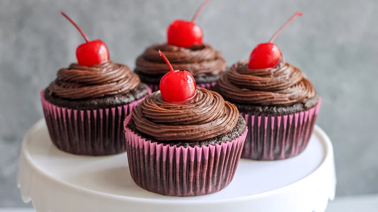 Plate of piecaken cupcakes with cherries on top