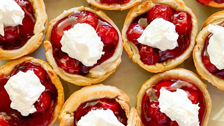 Mini cherry pies topped with whipped cream