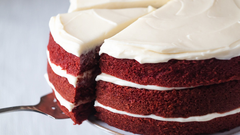 Red velvet cake with frosting and serving knife