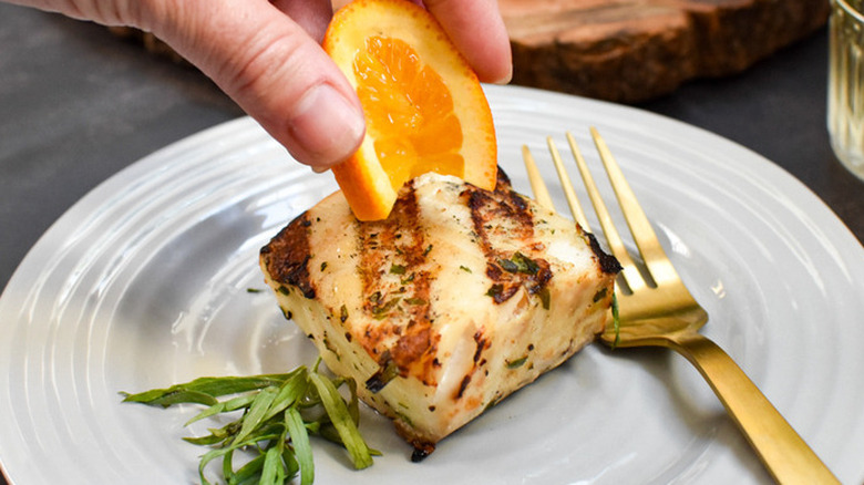Grilled fish getting a squeeze of orange