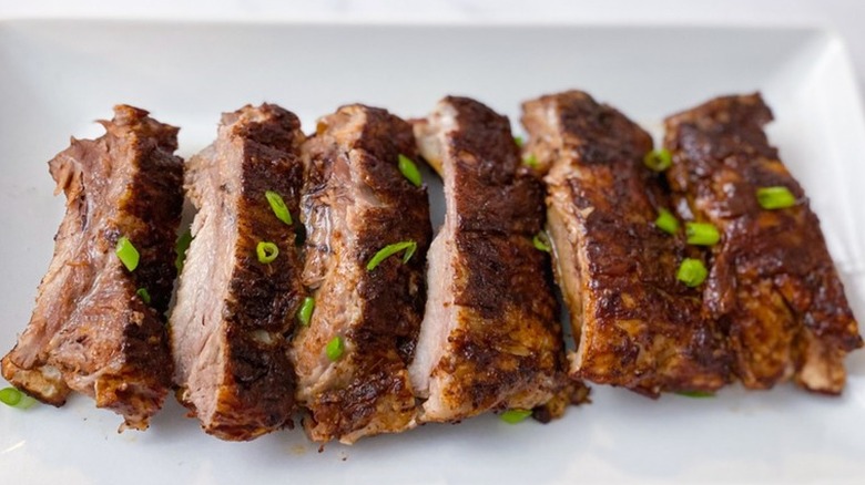 Row of cooked ribs on white plate