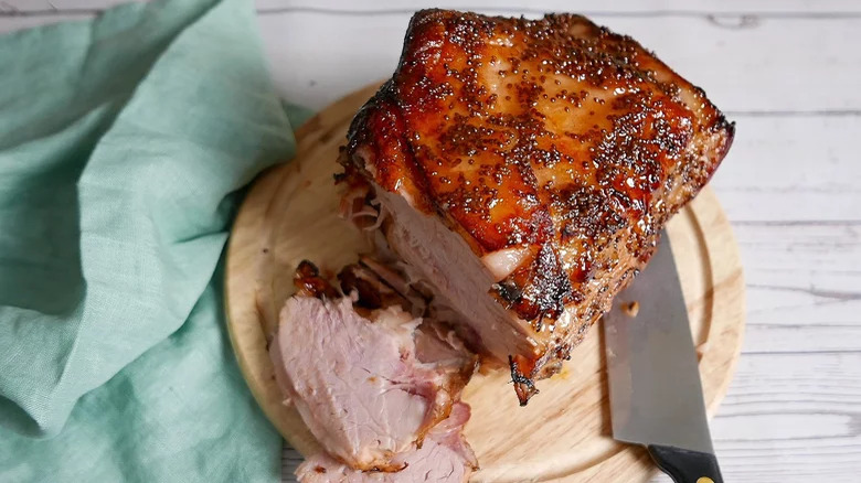 Glazed ham on a wooden board with a knife