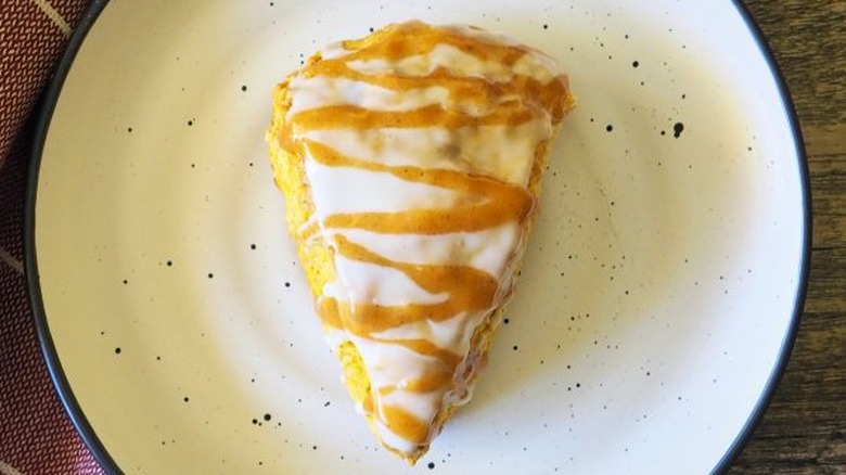 Triangular scone with orange and white icing.