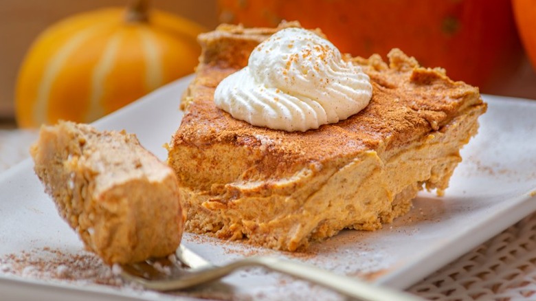 Slice of creamy pumpkin pie with whipped cream