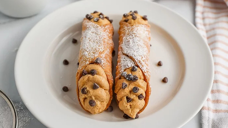 Two cannoli with orange cream and chocolate chips