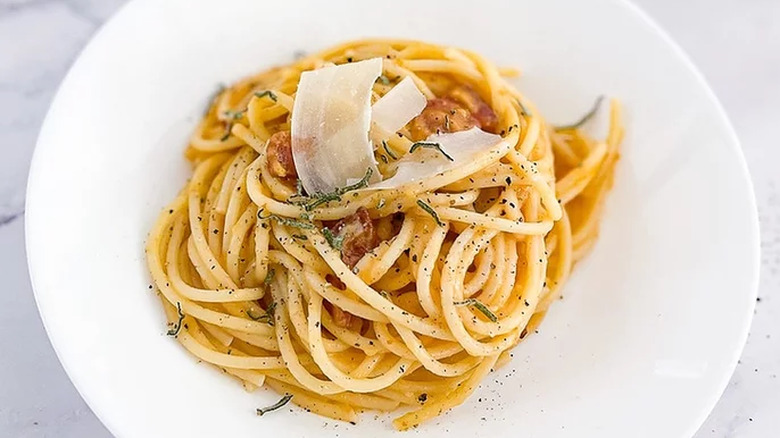 Spaghetti on plate with herbs and Parmesan curl