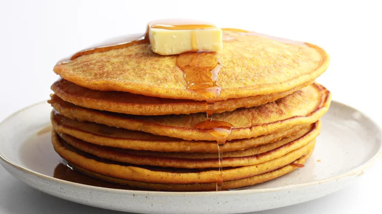 Stack of thin pumpkin pancakes with syrup.