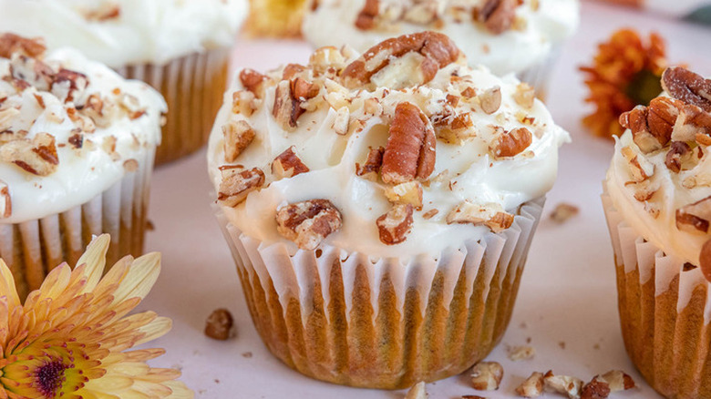 White-frosted pumpkin cupcakes with chopped nuts