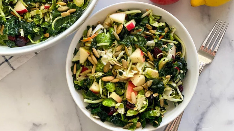 Bowl of kale salad with apple and pumpkin seeds