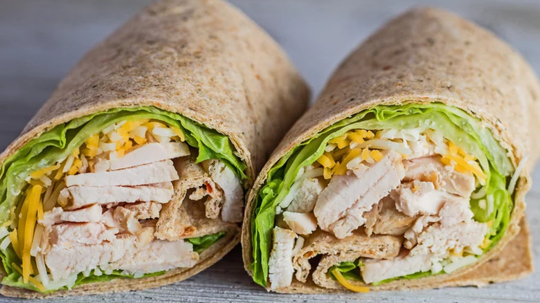 Wrap sandwiches with chicken, lettuce and cheese.