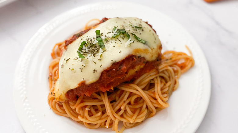 Sauce and cheese covered chicken on pasta