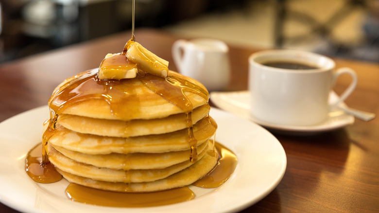 pouring maple syrup on pancakes