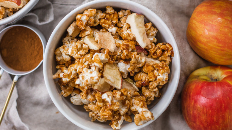 Bowl of caramel popcorn with apple pieces.