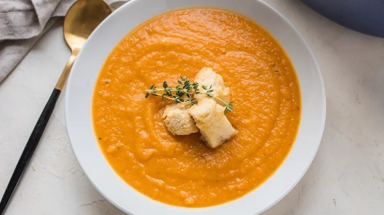 bowl of roasted root vegetable soup with croutons and spoon