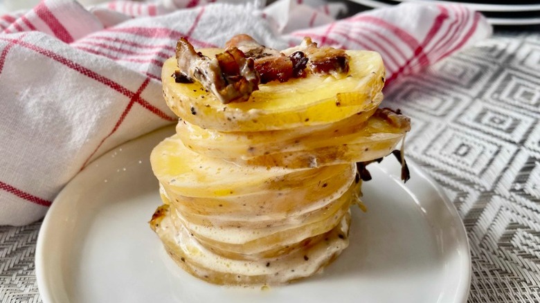 plate with stack of scalloped potatoes and dish towel