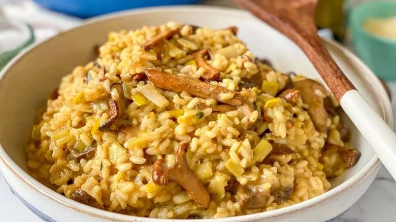 bowl of vegan mushroom risotto with wooden spoon