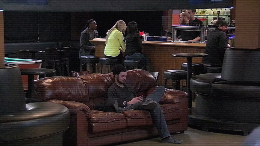 People sitting and talking at bar and one man on couch, screenshot from Bar Rescue