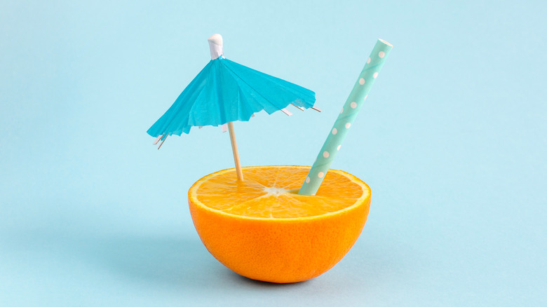 orange half with straw and umbrella