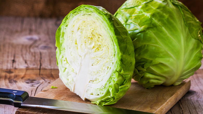 raw halved cabbage cutting board knife