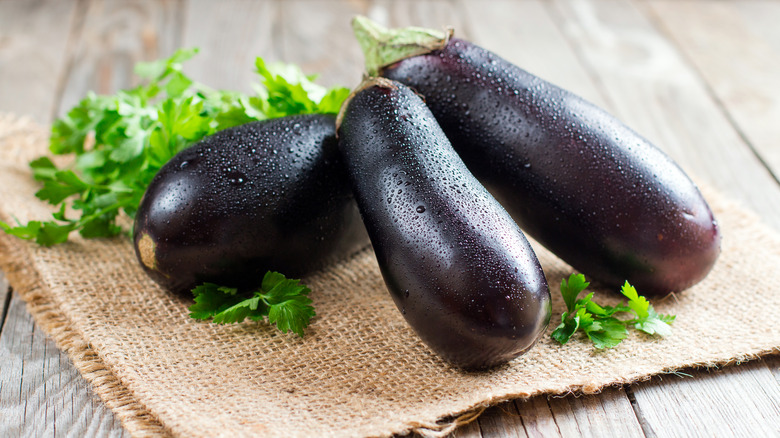 three whole purple eggplant parsley