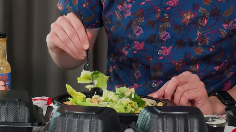 Person poking Caesar salad with fork