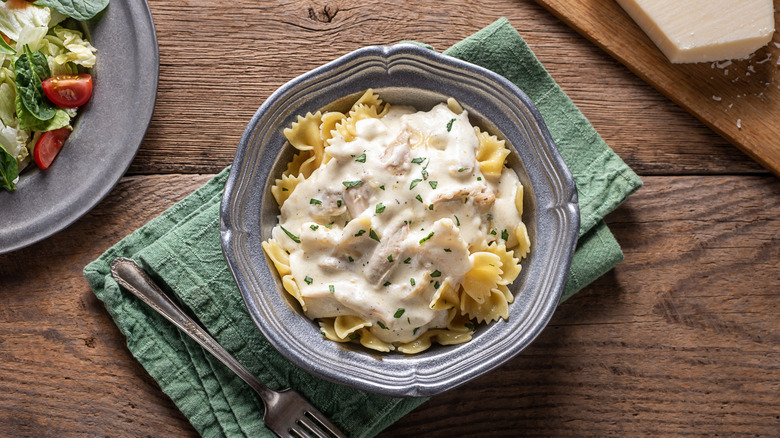 Chicken Alfredo sauce over bowl of bowtie pasta