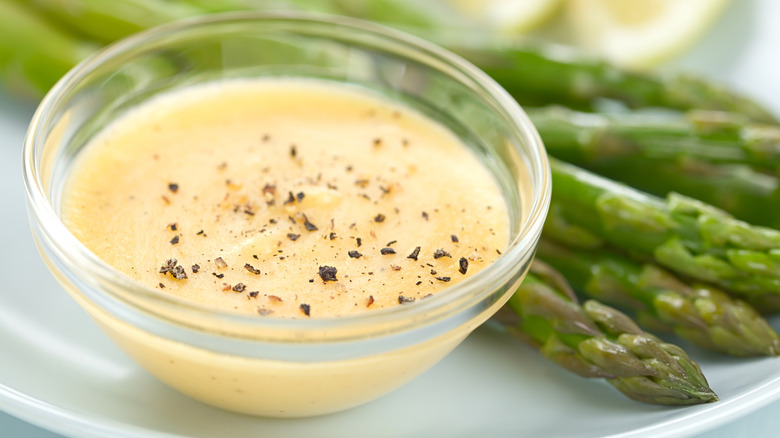 Small bowl lemon butter sauce with asparagus