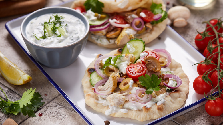 Chicken gyros on tray with tzatziki sauce