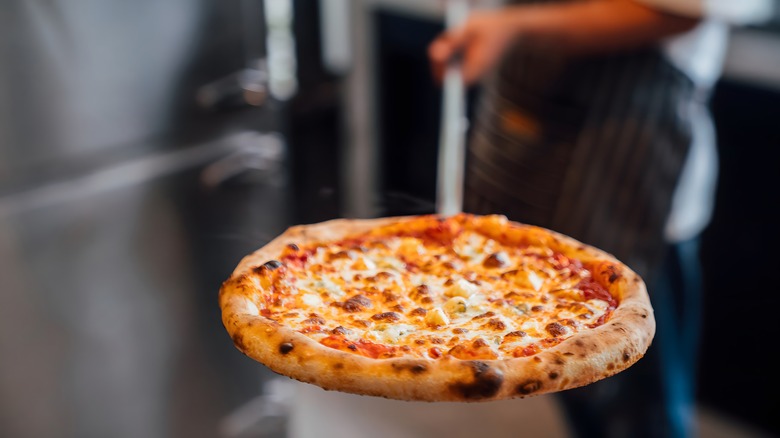 Person taking pizza from oven