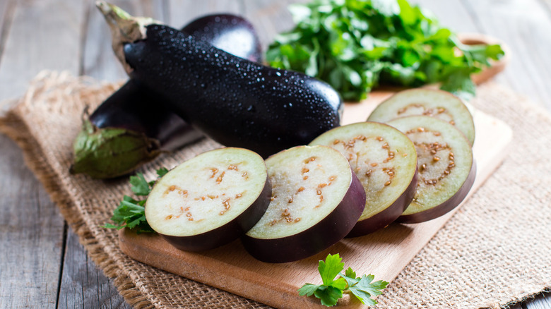 sliced and whole eggplant on cutting board