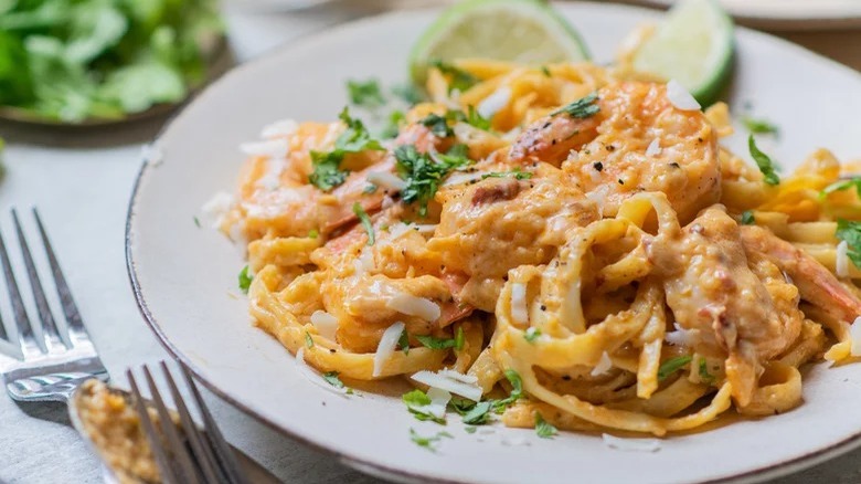 plate of creamy shrimp diablo with forks and limes