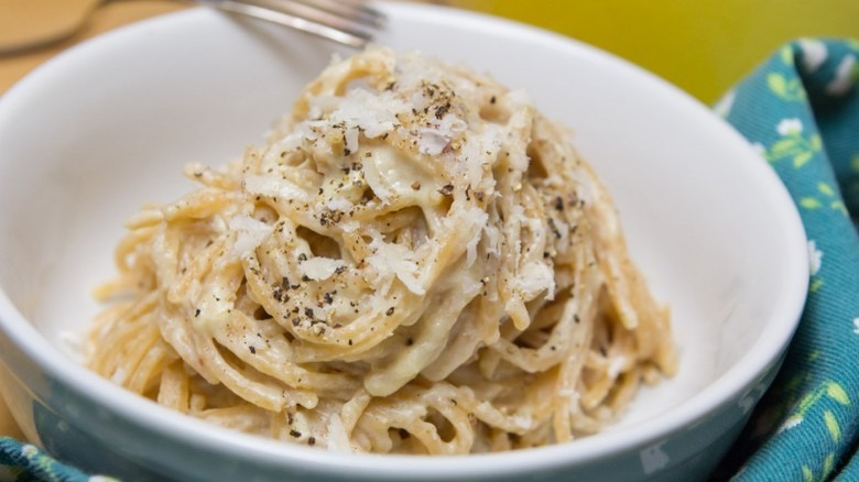 bowl of whole wheat pasta carbonara with fork and napkin