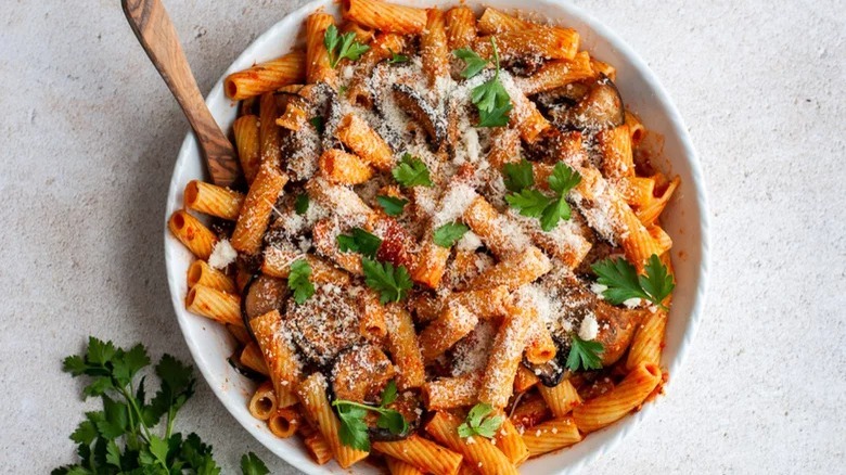 bowl of pasta alla norma with garnish and spoon