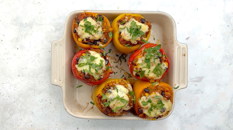 bell peppers stuffed with rice, beans and corn in baking dish