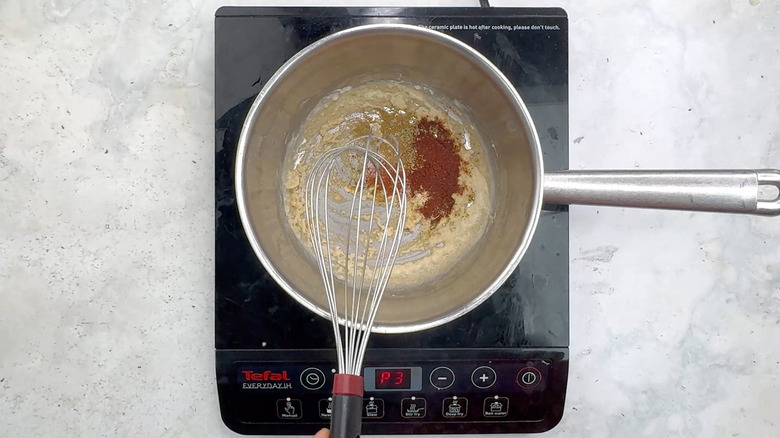 enchilada sauce spices in saucepan with whisk