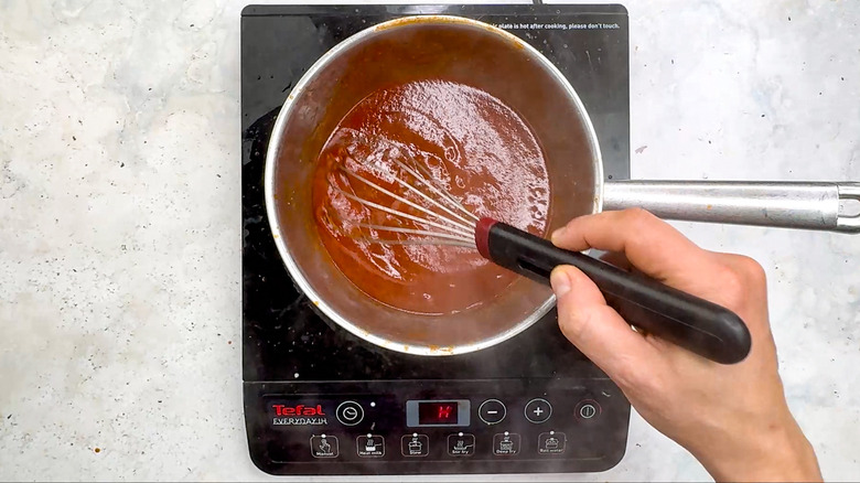 hand whisking enchilada sauce in saucepan