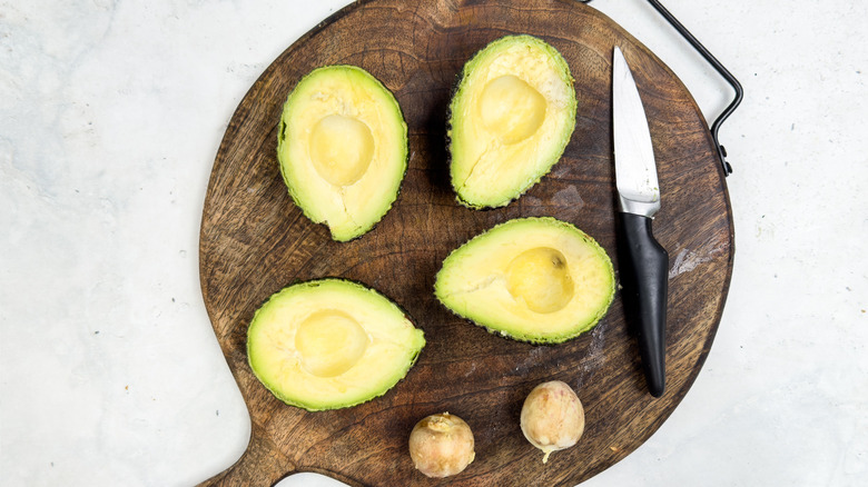 halved avocados on chopping board