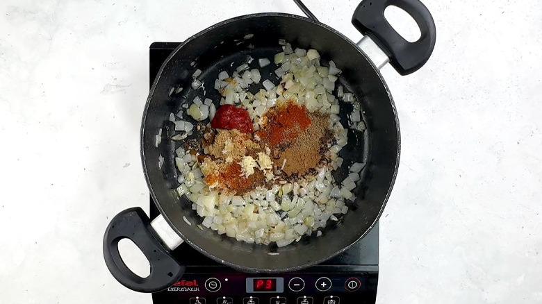 onion, spices and tomato paste in pan