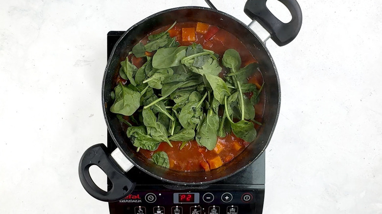 adding spinach to sweet potato tagine pot pie