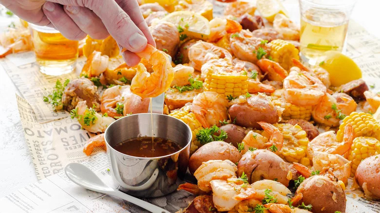 hand dipping shrimp in sauce