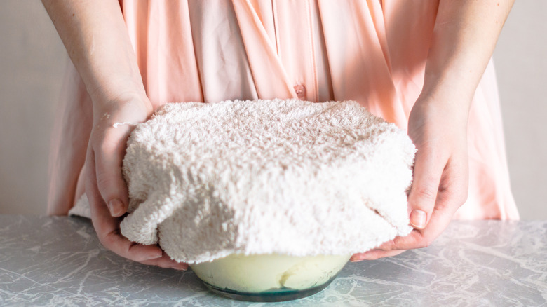 hands covering bowl with towel