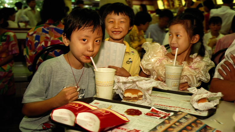 Three Chinese children eating happy meals