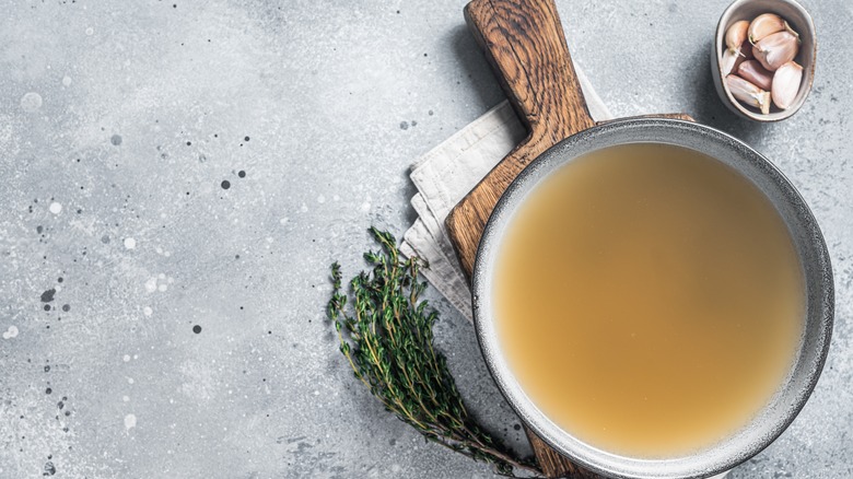 chicken stock in gray bowl on wood paddle