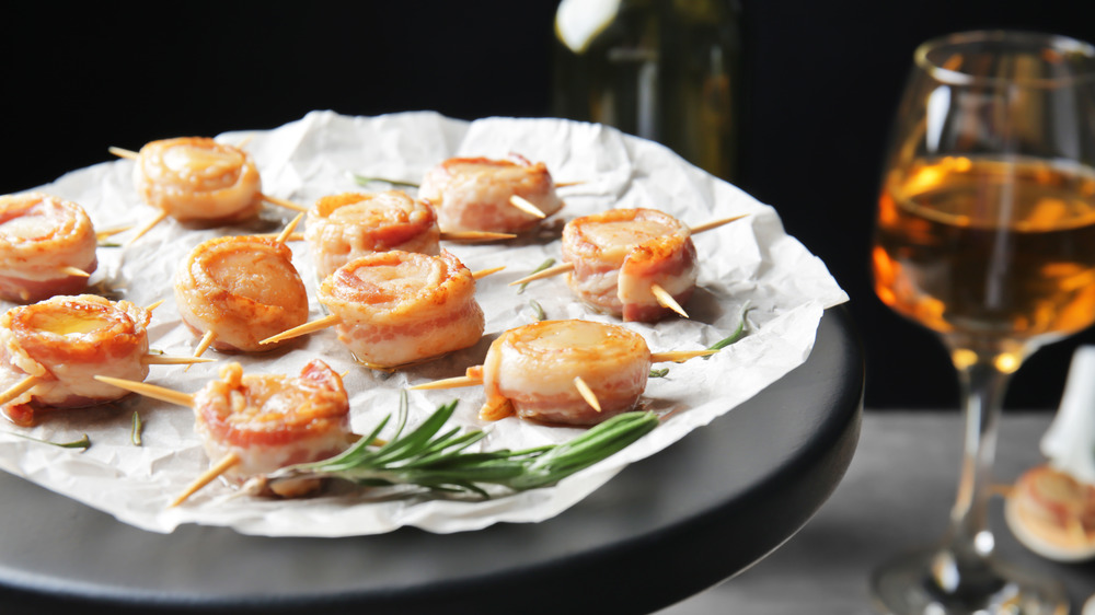 Bacon wrapped scallops on a plate with herbs