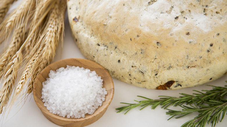 Loaf of bread next to bowl of salt and rosemary sprig