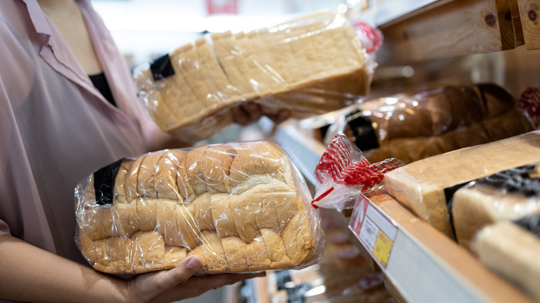 Person holding two loaves of bread