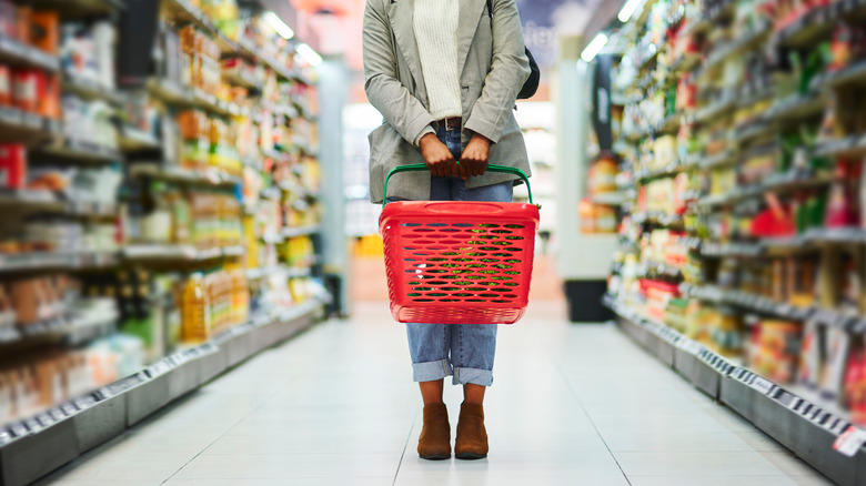 Person holding basket in grocery store